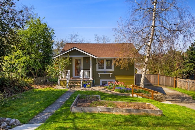 bungalow-style house featuring concrete driveway, a vegetable garden, a front lawn, and fence