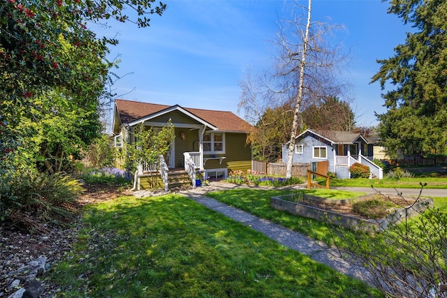 bungalow-style home with fence, covered porch, and a front yard