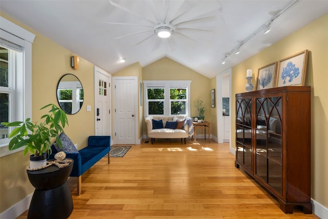 living area featuring ceiling fan, lofted ceiling, light wood-style flooring, and plenty of natural light