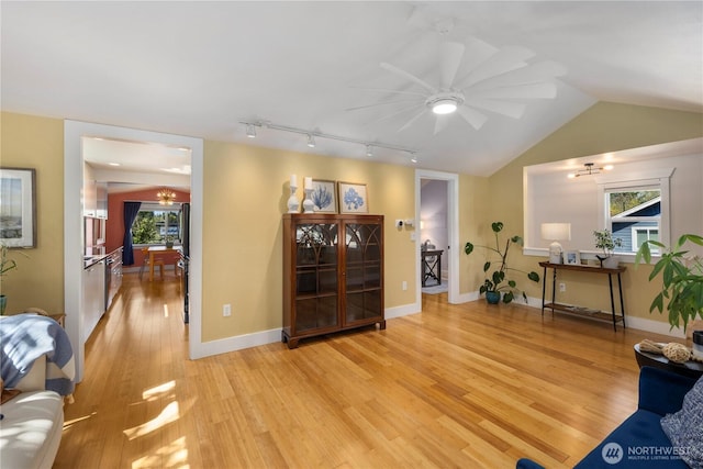 living room with light wood-type flooring, plenty of natural light, vaulted ceiling, and ceiling fan with notable chandelier