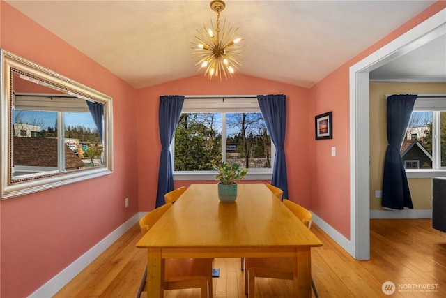 dining space with an inviting chandelier, lofted ceiling, light wood-style floors, and baseboards