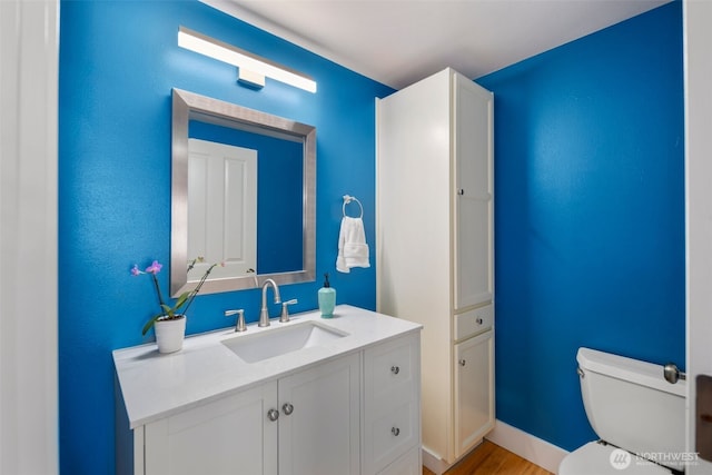 bathroom with wood finished floors, toilet, and vanity