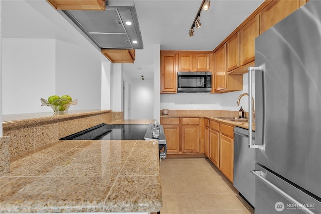 kitchen featuring light tile patterned floors, tile countertops, wall chimney exhaust hood, appliances with stainless steel finishes, and a sink