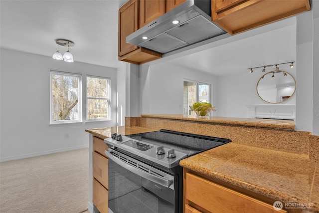 kitchen featuring brown cabinets, stainless steel electric range oven, light colored carpet, ventilation hood, and baseboards