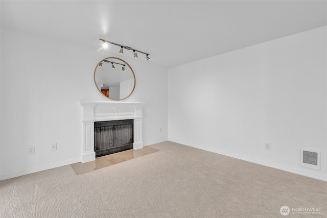 unfurnished living room with a fireplace with flush hearth, visible vents, baseboards, carpet, and rail lighting