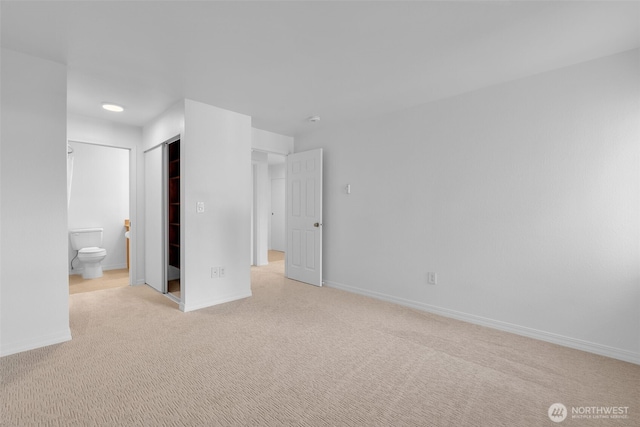 unfurnished bedroom featuring a closet, carpet, connected bathroom, and baseboards