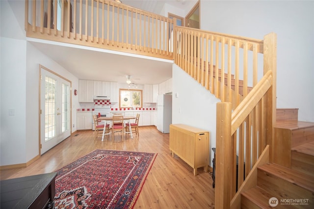 interior space featuring french doors, baseboards, a high ceiling, and wood finished floors