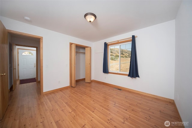 unfurnished bedroom featuring light wood-style floors, a closet, visible vents, and baseboards