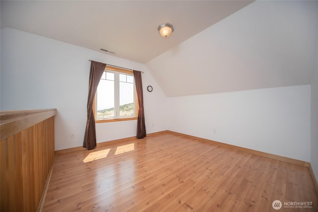 additional living space featuring vaulted ceiling, visible vents, light wood-style flooring, and baseboards