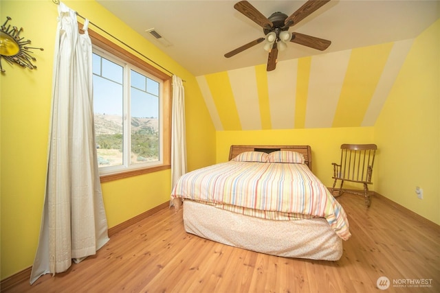 bedroom with lofted ceiling, a ceiling fan, visible vents, and wood finished floors