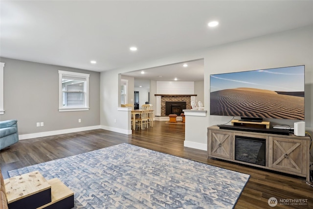 living area featuring dark wood-style floors, a fireplace, baseboards, and recessed lighting