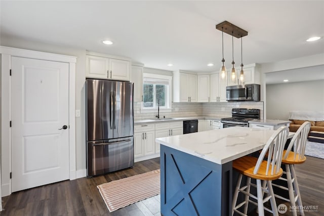 kitchen with a sink, white cabinets, appliances with stainless steel finishes, backsplash, and dark wood-style floors