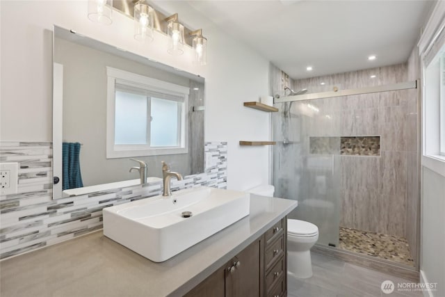 full bathroom featuring decorative backsplash, a shower stall, toilet, and vanity