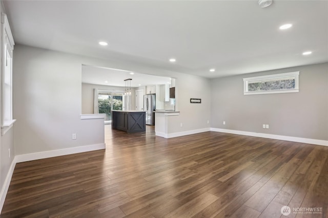 unfurnished living room featuring dark wood-type flooring, recessed lighting, and baseboards