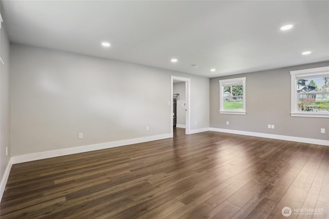 empty room featuring recessed lighting, baseboards, a healthy amount of sunlight, and dark wood-style floors