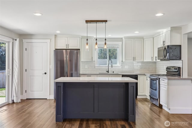 kitchen with a sink, appliances with stainless steel finishes, light countertops, and a healthy amount of sunlight