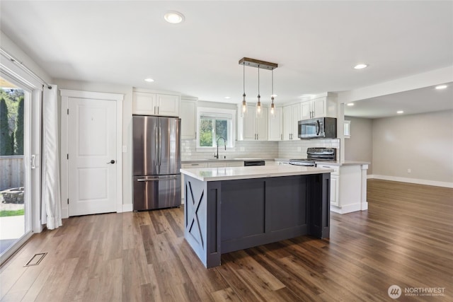 kitchen with a sink, light countertops, stainless steel appliances, white cabinetry, and dark wood-type flooring