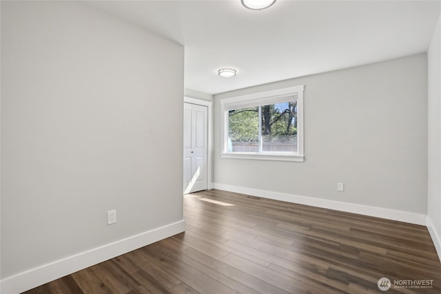 empty room featuring baseboards, dark wood finished floors, and visible vents