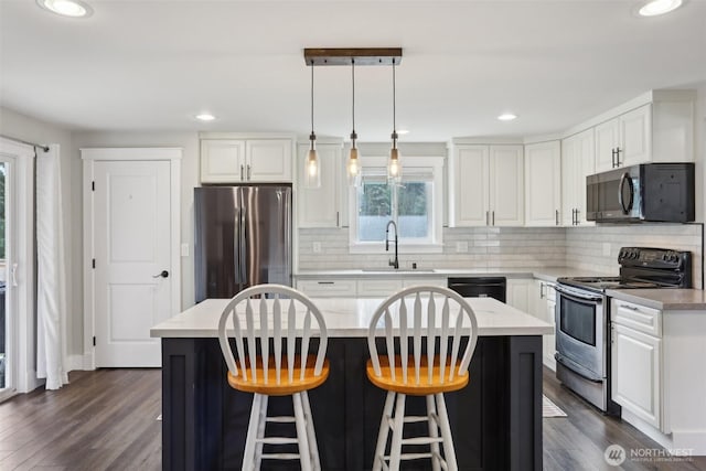 kitchen featuring a sink, light countertops, a breakfast bar, stainless steel appliances, and white cabinetry