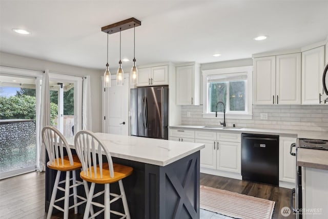 kitchen with white cabinets, a sink, dishwasher, freestanding refrigerator, and backsplash