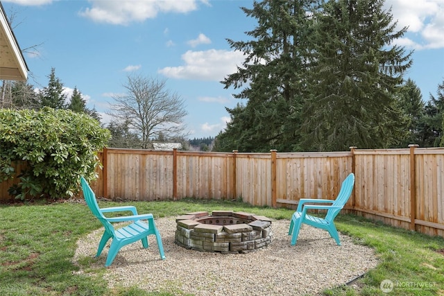 view of play area with a fenced backyard, a lawn, and a fire pit