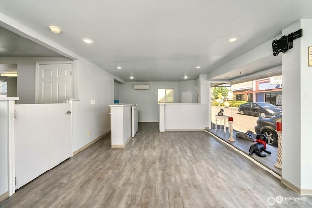 clothes washing area with recessed lighting, a wall unit AC, baseboards, and wood finished floors