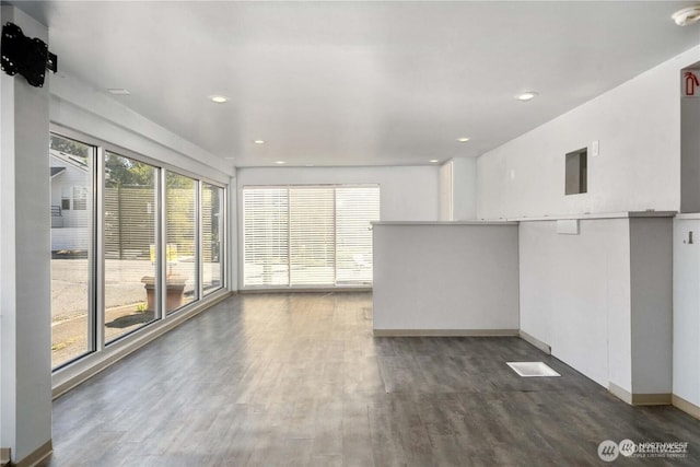 unfurnished living room featuring baseboards, dark wood-type flooring, and recessed lighting