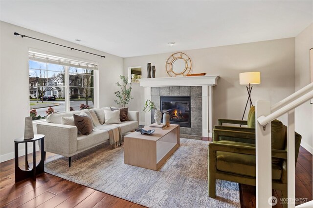 living room featuring baseboards, dark wood-type flooring, and a tile fireplace