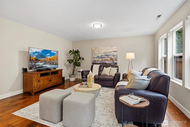 living area featuring wood finished floors, visible vents, and baseboards