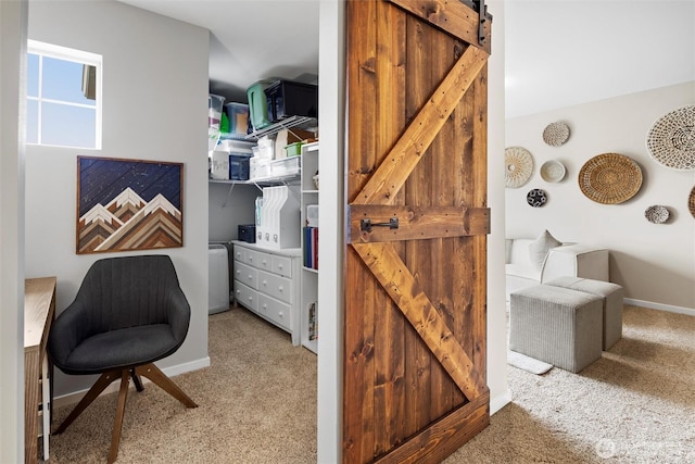 carpeted office space with a barn door and baseboards