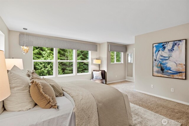 carpeted bedroom with an inviting chandelier and baseboards