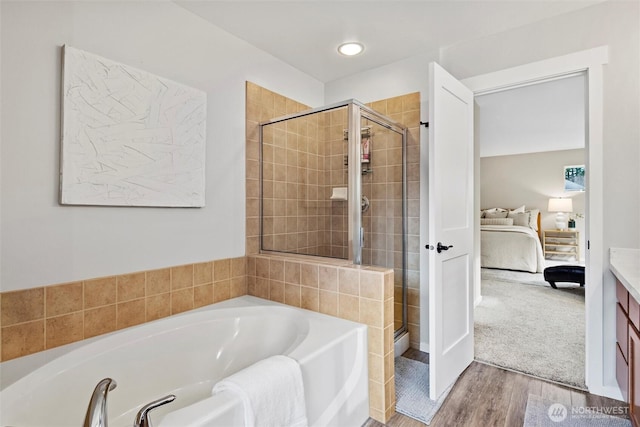 full bathroom with a bath, connected bathroom, a shower stall, and wood finished floors