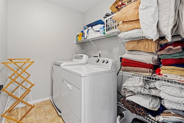 washroom featuring baseboards, light tile patterned flooring, laundry area, and washing machine and clothes dryer