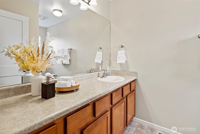 bathroom with double vanity, visible vents, baseboards, and a sink