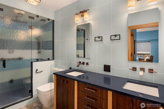 bathroom with a stall shower, tile walls, and vanity