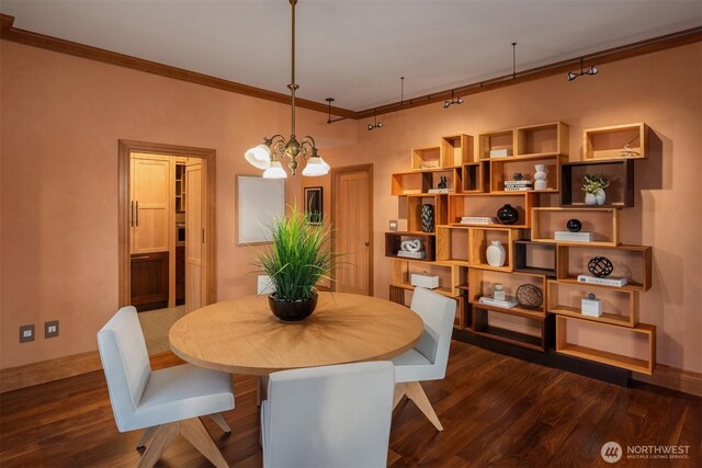 dining room featuring ornamental molding, dark wood finished floors, and an inviting chandelier