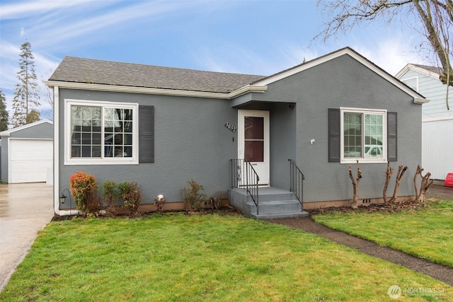 ranch-style home with an outbuilding, a detached garage, stucco siding, a shingled roof, and a front lawn