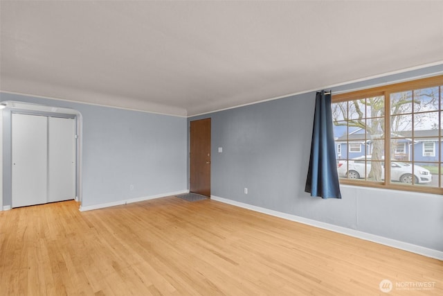 interior space with ornamental molding, light wood-type flooring, and baseboards