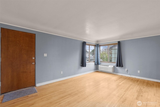 empty room featuring light wood-type flooring, crown molding, and baseboards