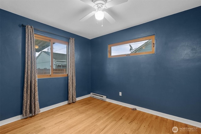 empty room with baseboard heating, wood finished floors, and baseboards