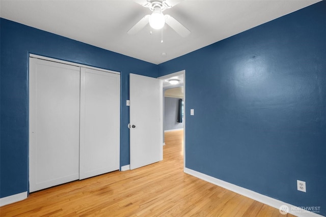 unfurnished bedroom featuring a ceiling fan, a closet, baseboards, and wood finished floors