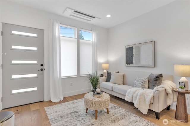 living room with recessed lighting, visible vents, baseboards, and wood finished floors