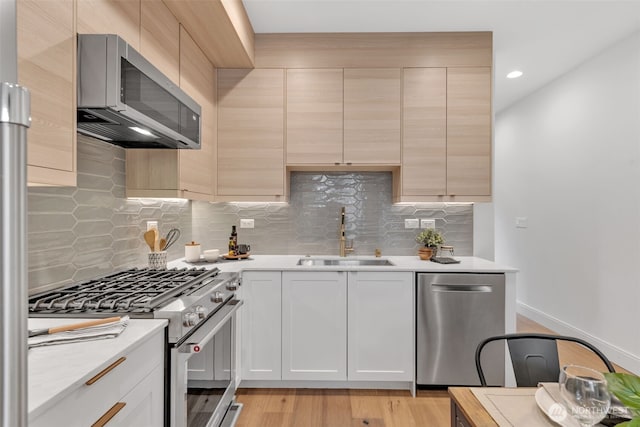 kitchen featuring stainless steel appliances, light wood-type flooring, light countertops, and a sink