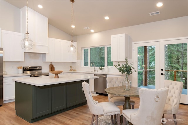 kitchen with a sink, visible vents, white cabinetry, light countertops, and appliances with stainless steel finishes