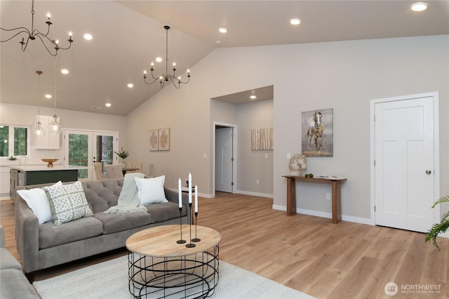 living area with light wood finished floors, high vaulted ceiling, french doors, and a chandelier