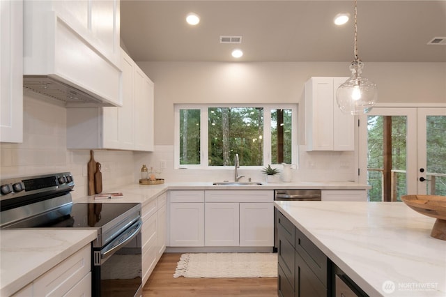 kitchen with stainless steel electric range oven, premium range hood, a sink, and white cabinetry