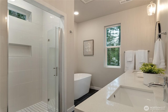 full bathroom with double vanity, a stall shower, visible vents, a freestanding tub, and a sink