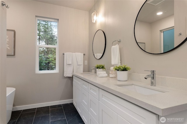 bathroom with a sink, a freestanding bath, baseboards, and double vanity