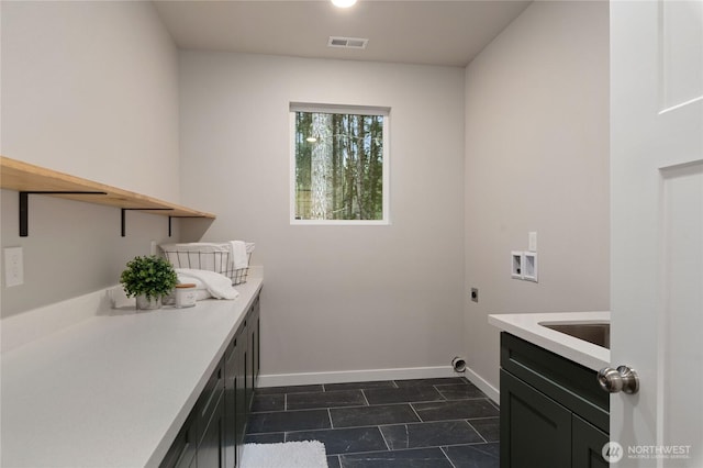 laundry area with baseboards, visible vents, hookup for a washing machine, electric dryer hookup, and a sink