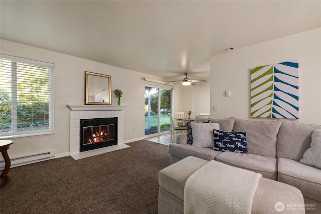 carpeted living room with visible vents, baseboards, ceiling fan, a brick fireplace, and a baseboard heating unit